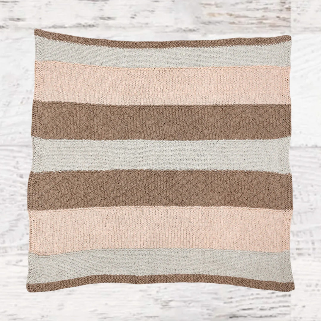 Fuzzy Goat knit baby blanket kit featuring a soft striped textured throw in neutral pink, beige, and white tones.