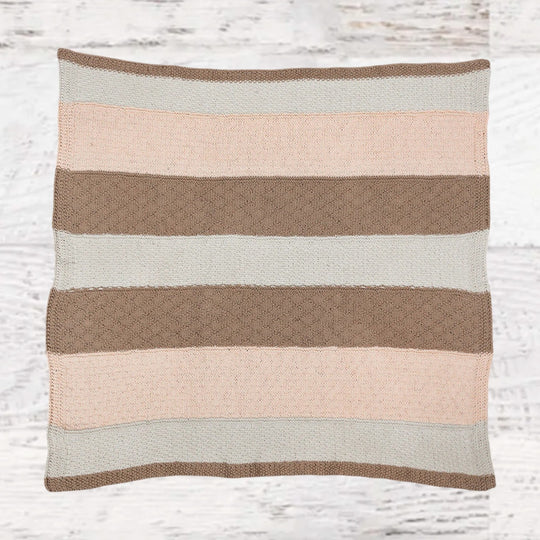 Fuzzy Goat knit baby blanket kit featuring a soft striped textured throw in neutral pink, beige, and white tones.
